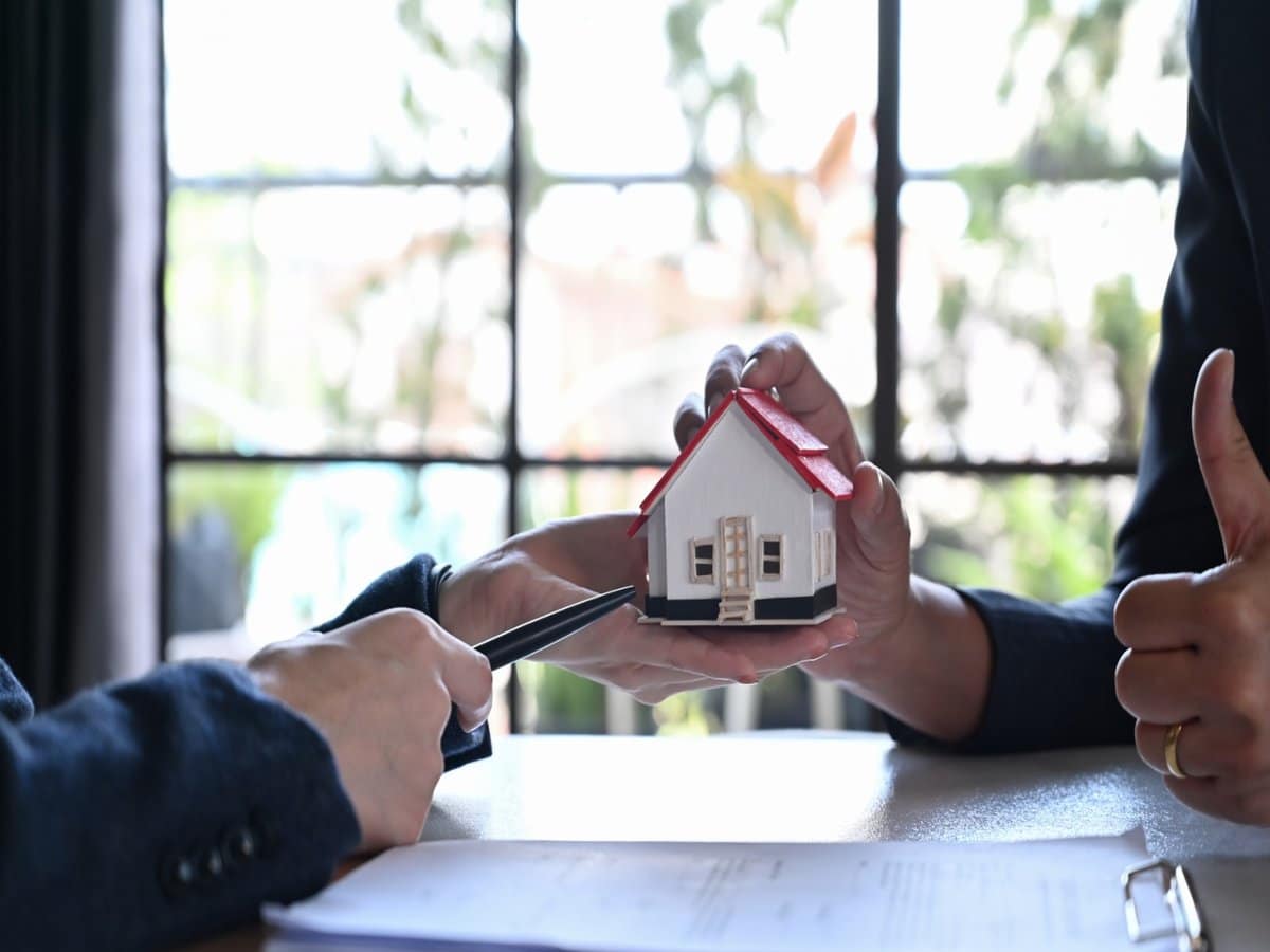 Real estate broker in San Antonio TX handing a miniature house model during a client meeting.