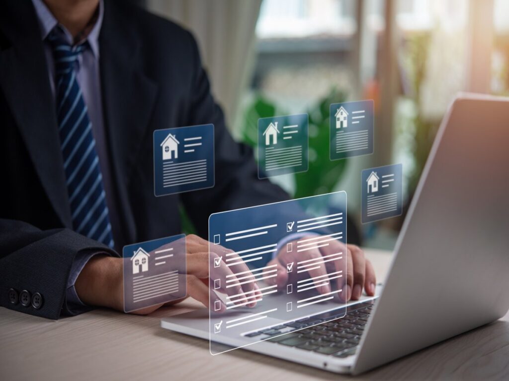 Agent reviewing property data Real estate broker in San Antonio TX researching property listings on a laptop with digital housing icons.