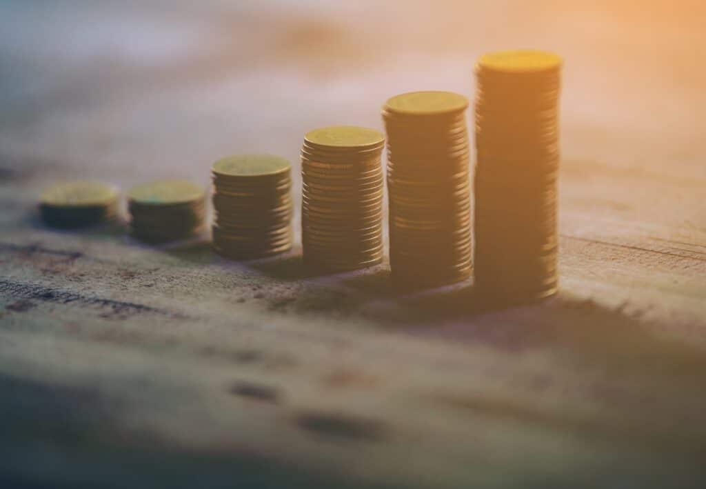 Growing savings concept Stacks of coins arranged in increasing height on a wooden surface.