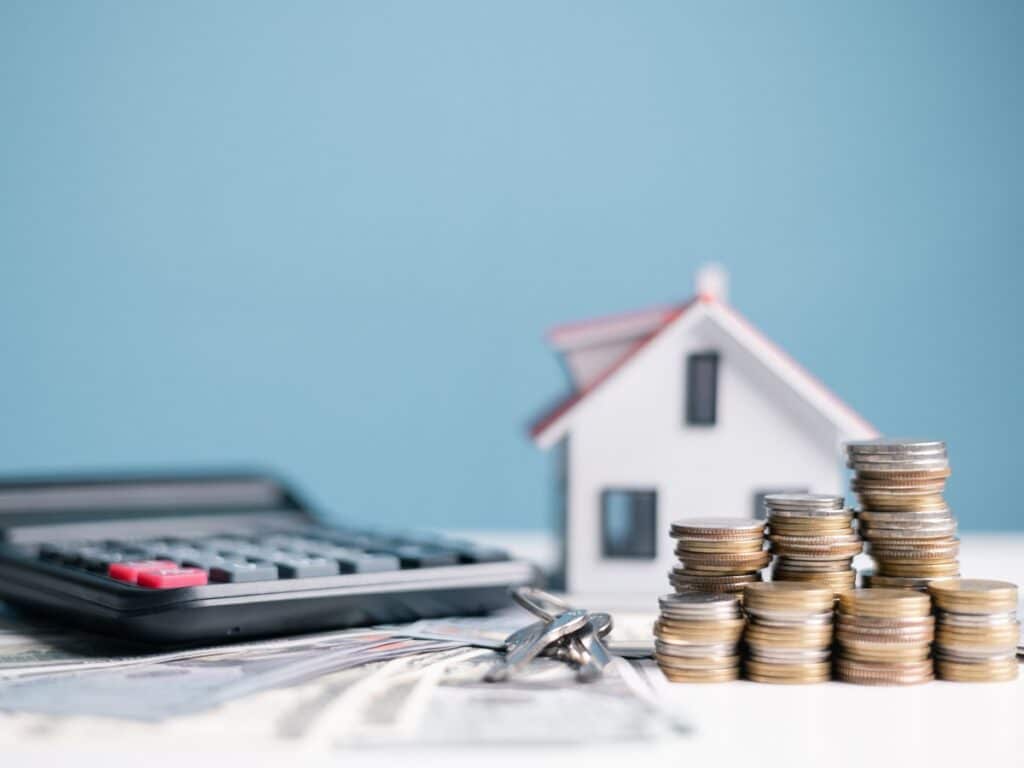 San Antonio home value concept Calculator, model house, and stacked coins illustrating median home price in san antonio tx.