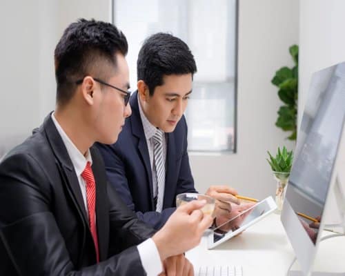 Two business professionals reviewing information on a tablet in an office setting